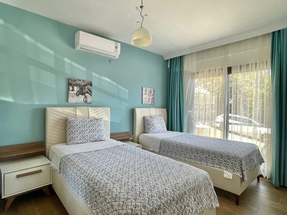 Yatak odası — iki tek kişilik yatak, mint yeşili duvar ve balkon kapısı