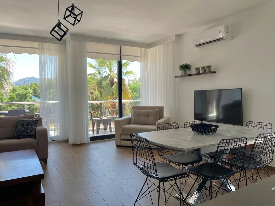 Salonun geniş görünümü — yemek masası ve balkon kapıları