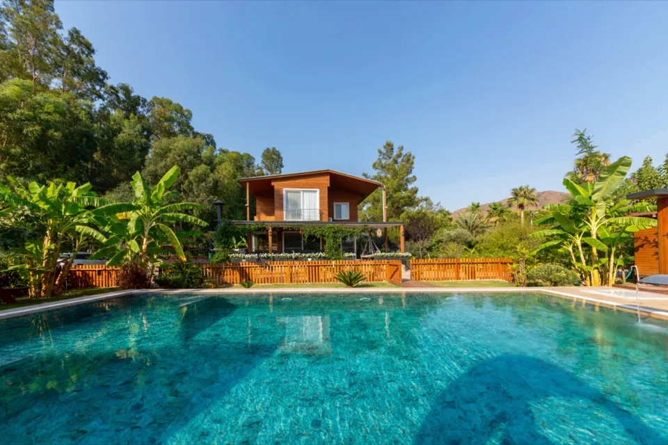 Villa Kaktüs — iki katlı ahşap villanın dış cephesi, çiçekli teras ve cam kapılar