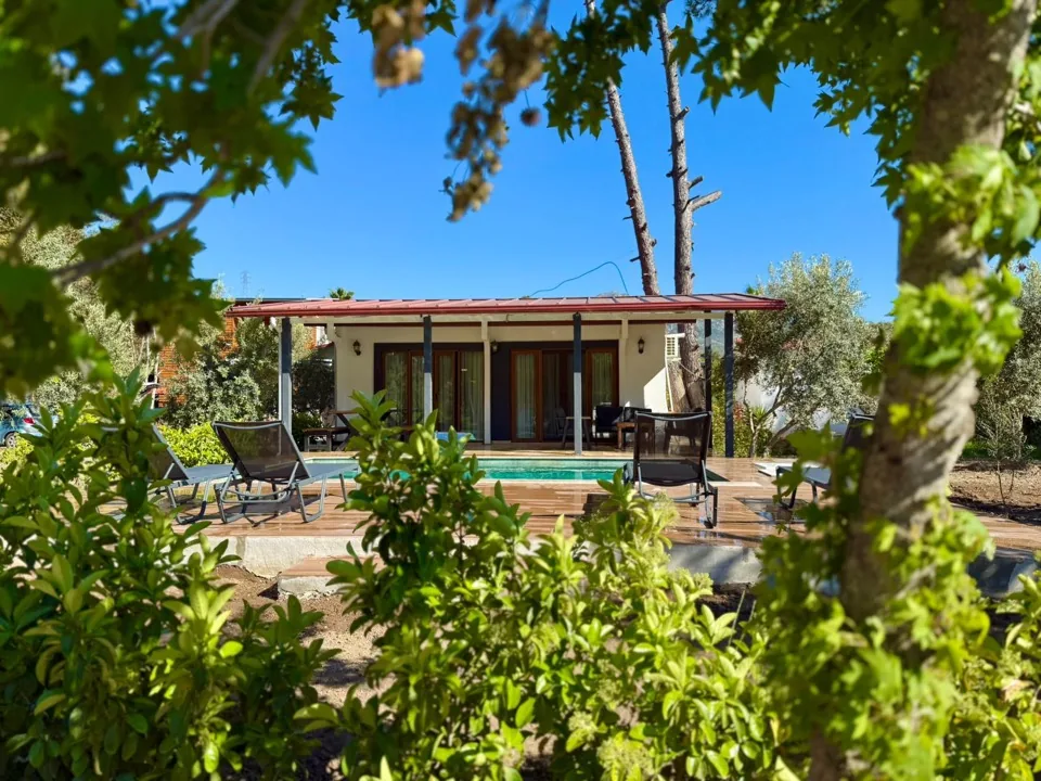 Ağaç dallarının arasından havuz ve villa